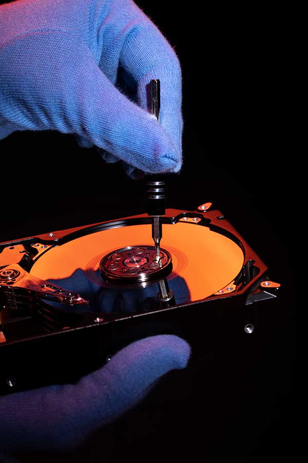 Gloved hands inspecting the internal components of a defective product in a dark forensic lab