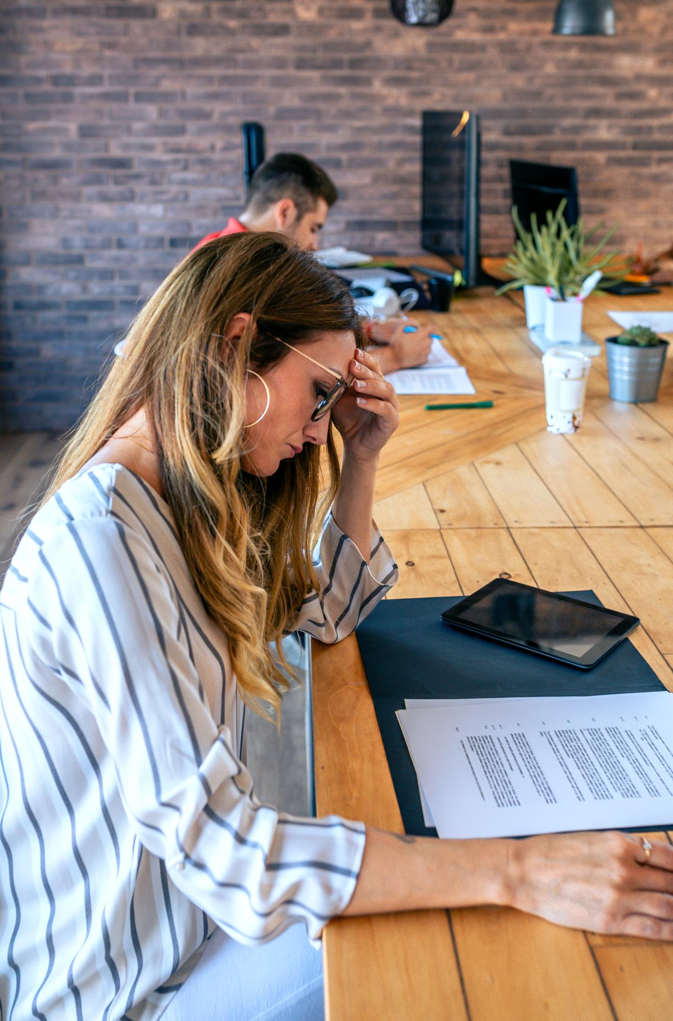 Woman reviewing insurance claim denial documents at an office desk